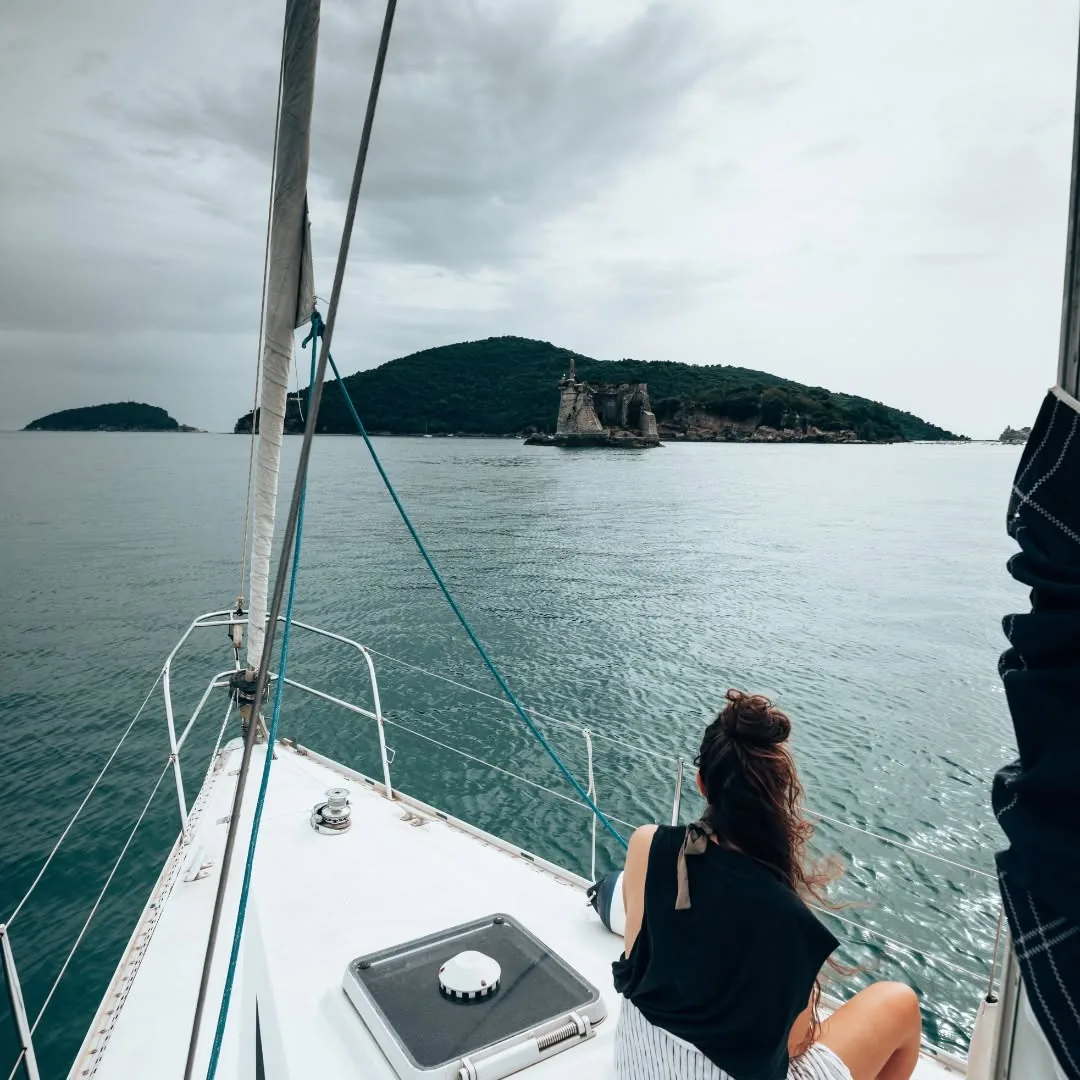 A sailboat approaching a small green island on calm water